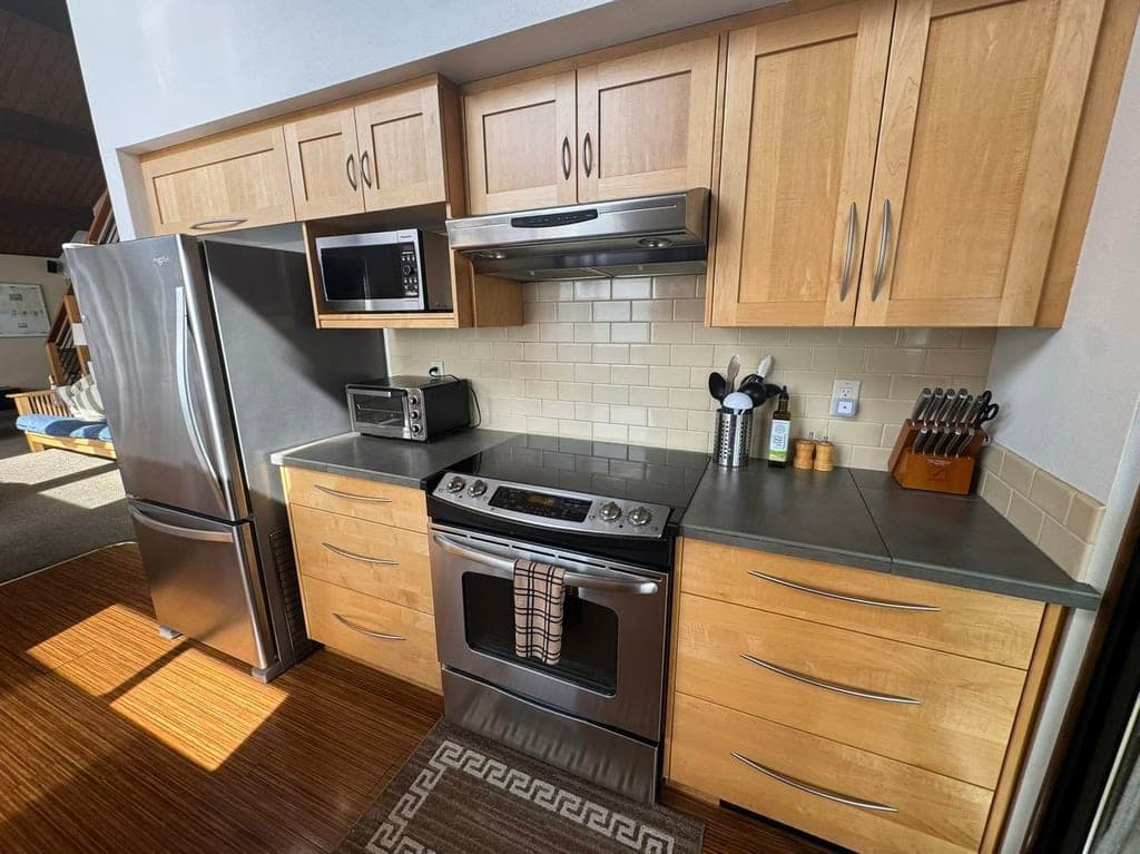Clean kitchen with new stainless steel appliances and tile backsplash